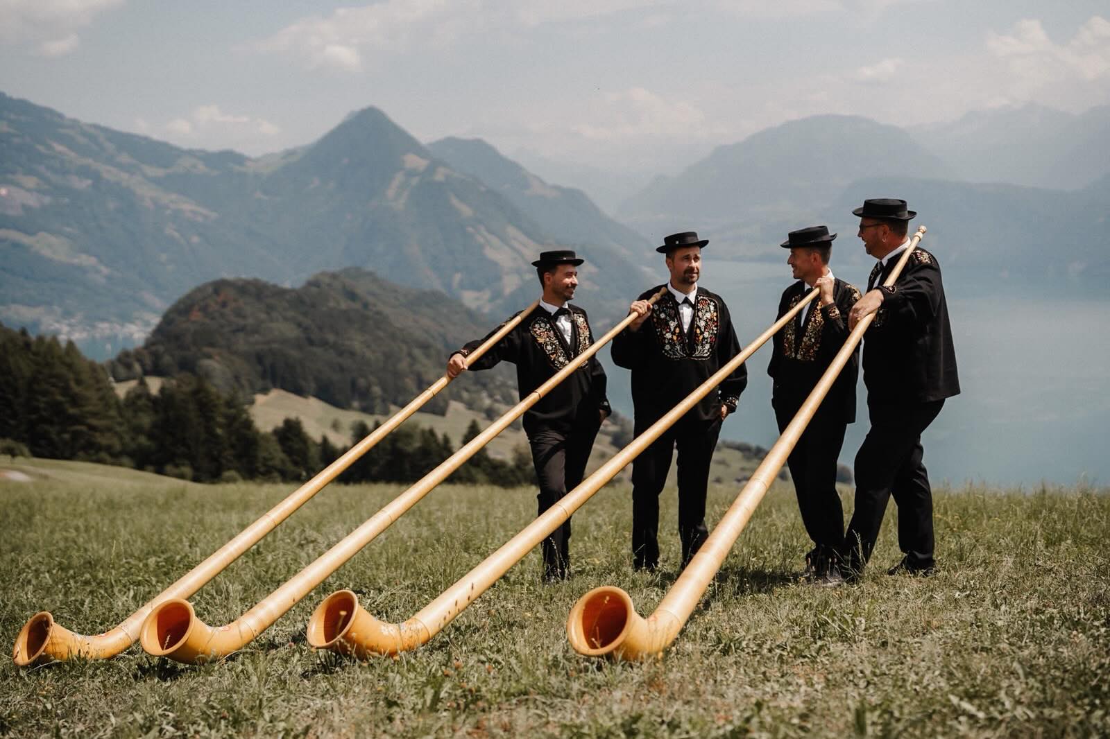Die vier Brüder spielen Alphorn auf einer Bergwiese